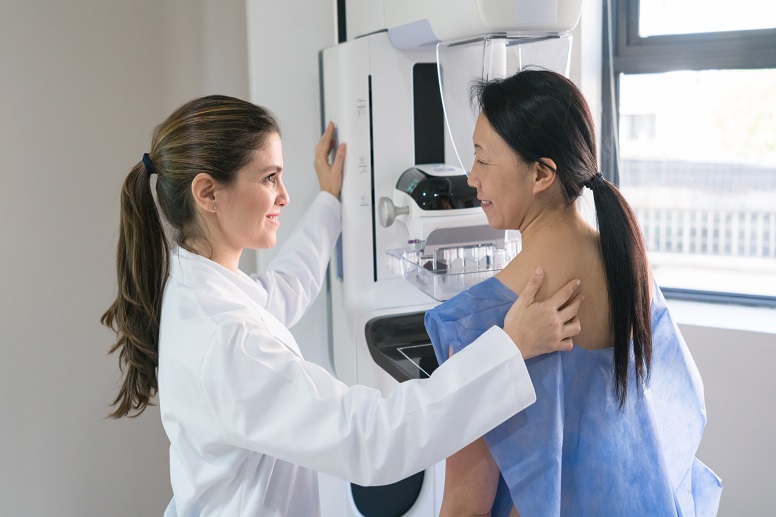 Female doctor helping a patient get in position for a mammogram