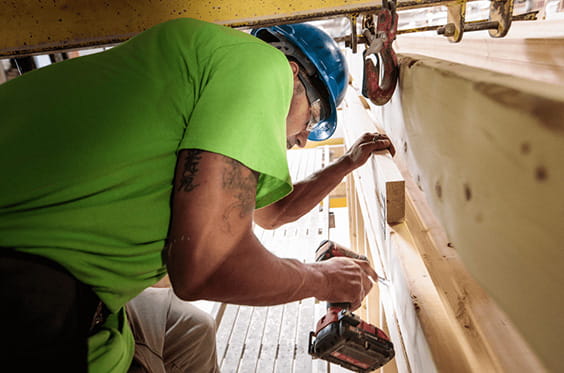 A carpenter is operating a power drill on a construction site