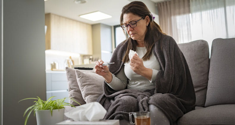 A sick woman reading a thermometer