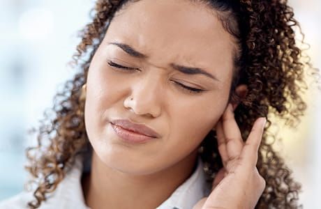 A woman experiencing ringing of the ears, known as tinnitus. 