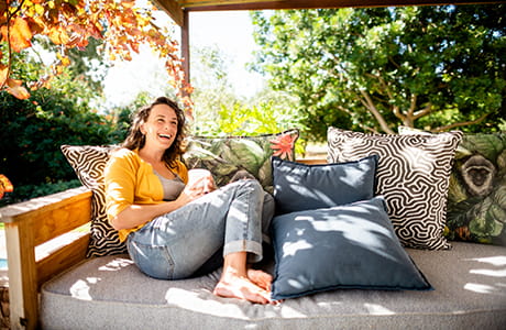 A woman with a warm smile relaxing on a chair outside. 