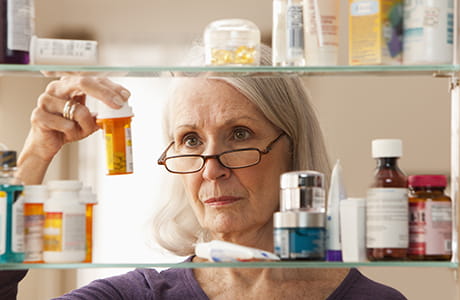 Woman looking in medicine cabinet. 