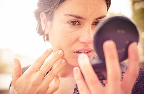 A woman checking for sunspots in the mirror.