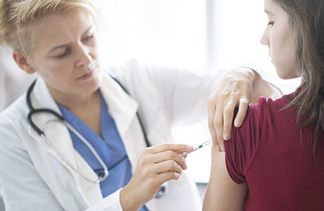 Female doctor vaccinating young woman in her office