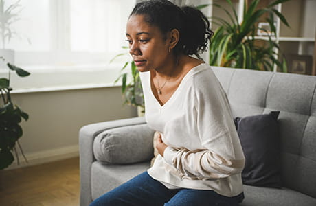 Woman holding her stomach with IBS pain.