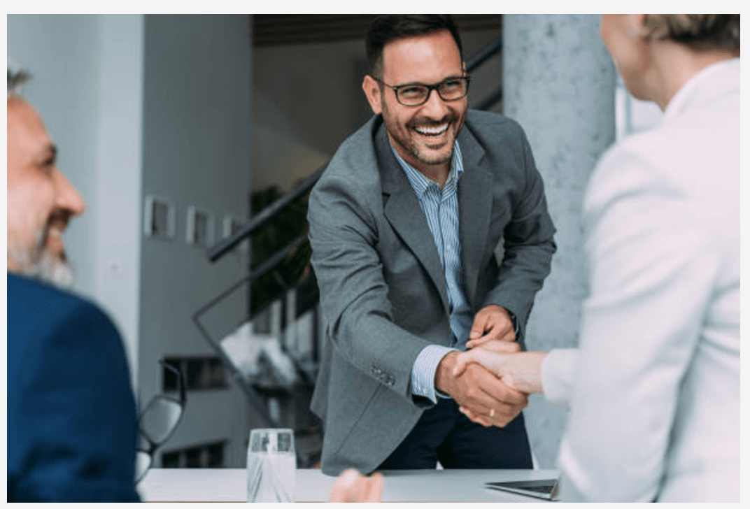 A businessman shakes hands with a woman in a meeting