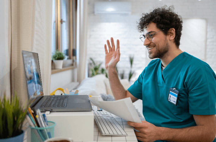 A doctor speaks with a patient remotely through a laptop