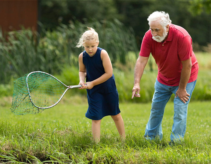 An elderly man in a wheelchair high-fives a younger woman