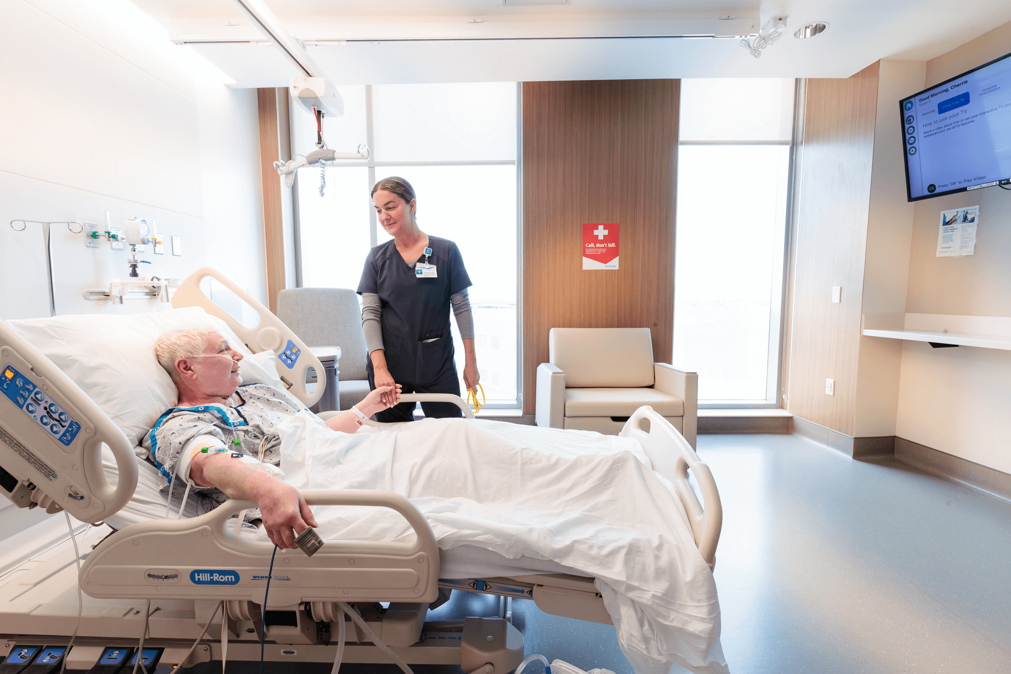 A nurse looks over a senior patient in a hospital bed