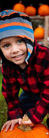 A young child holding a pumpkin