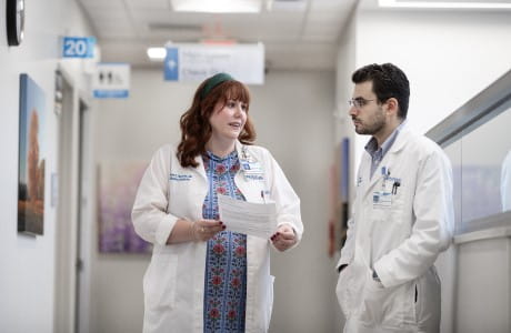 Two palliative medicine specialist talk in a hospital hallway