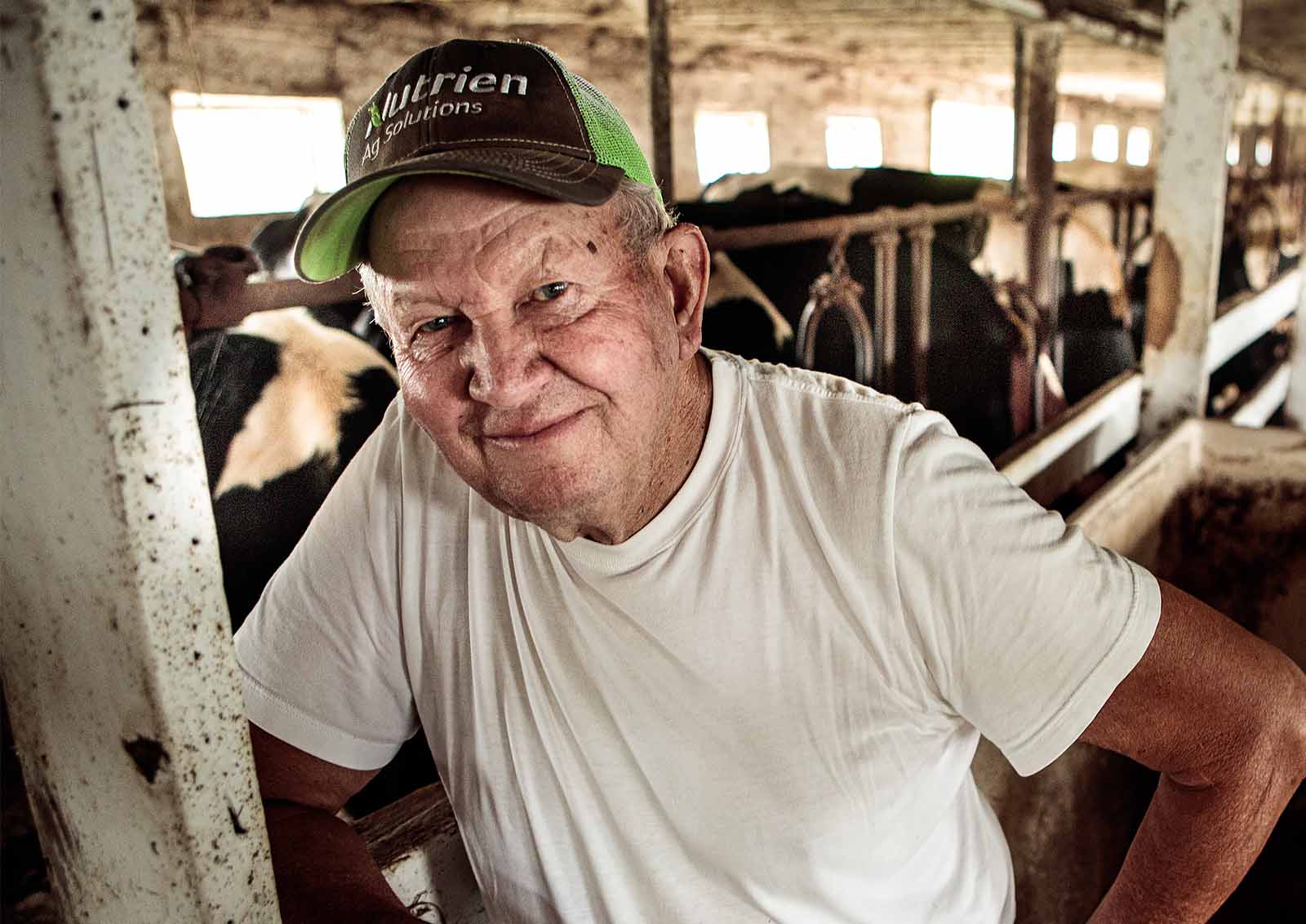 A local dairy farmer takes a moment from his busy day to have a picture taken in the barn.