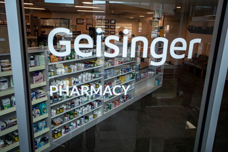 The words "Geisinger Pharmacy" on glass looking into the pharmacy